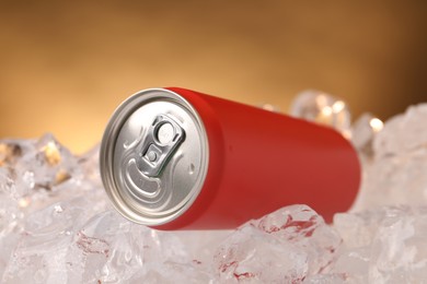 Photo of Refreshing drink in can on ice cubes against golden background, closeup