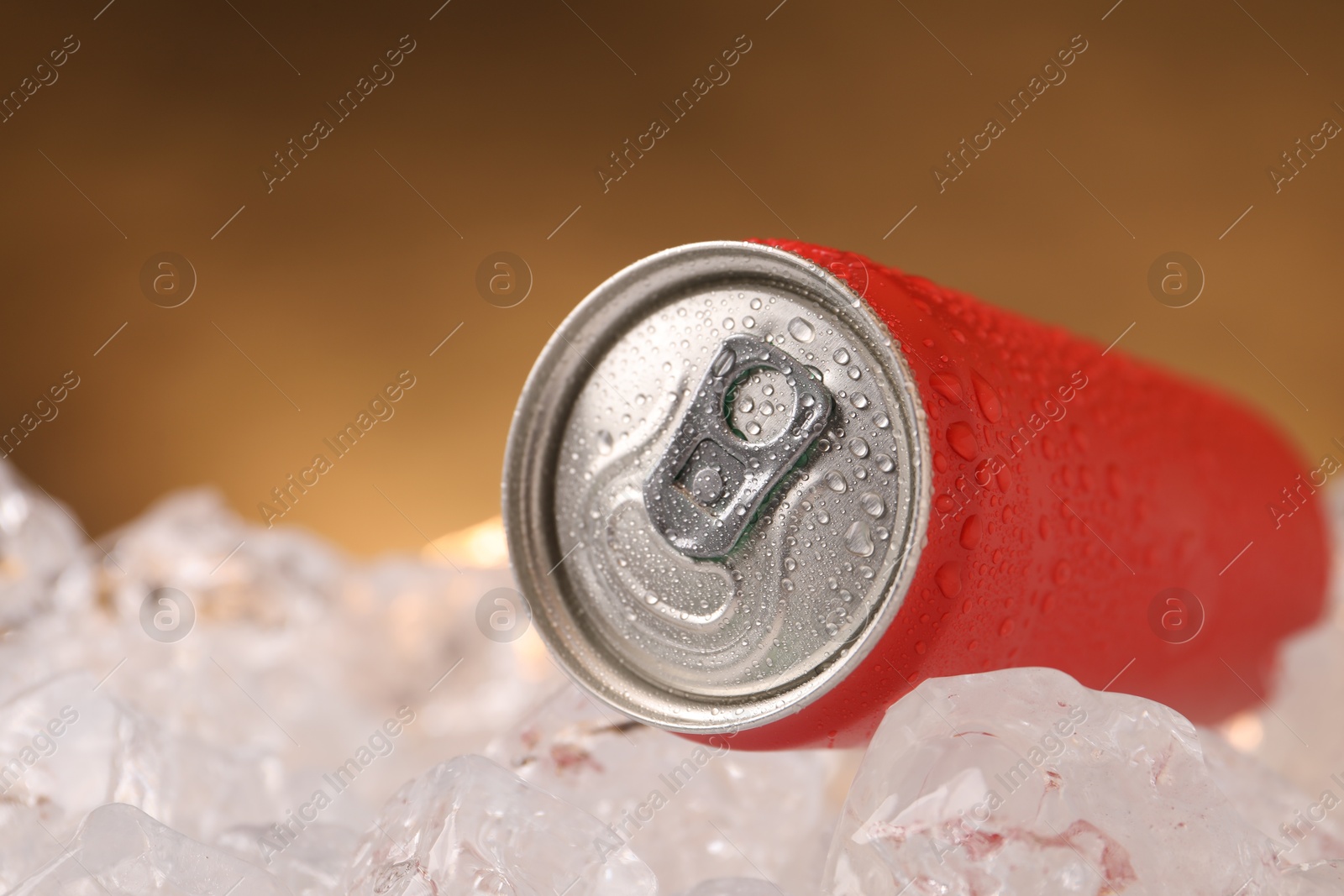 Refreshing drink in can on ice cubes against golden background, closeup Photo of Refreshing drink in can on ice cubes against golden background, closeup