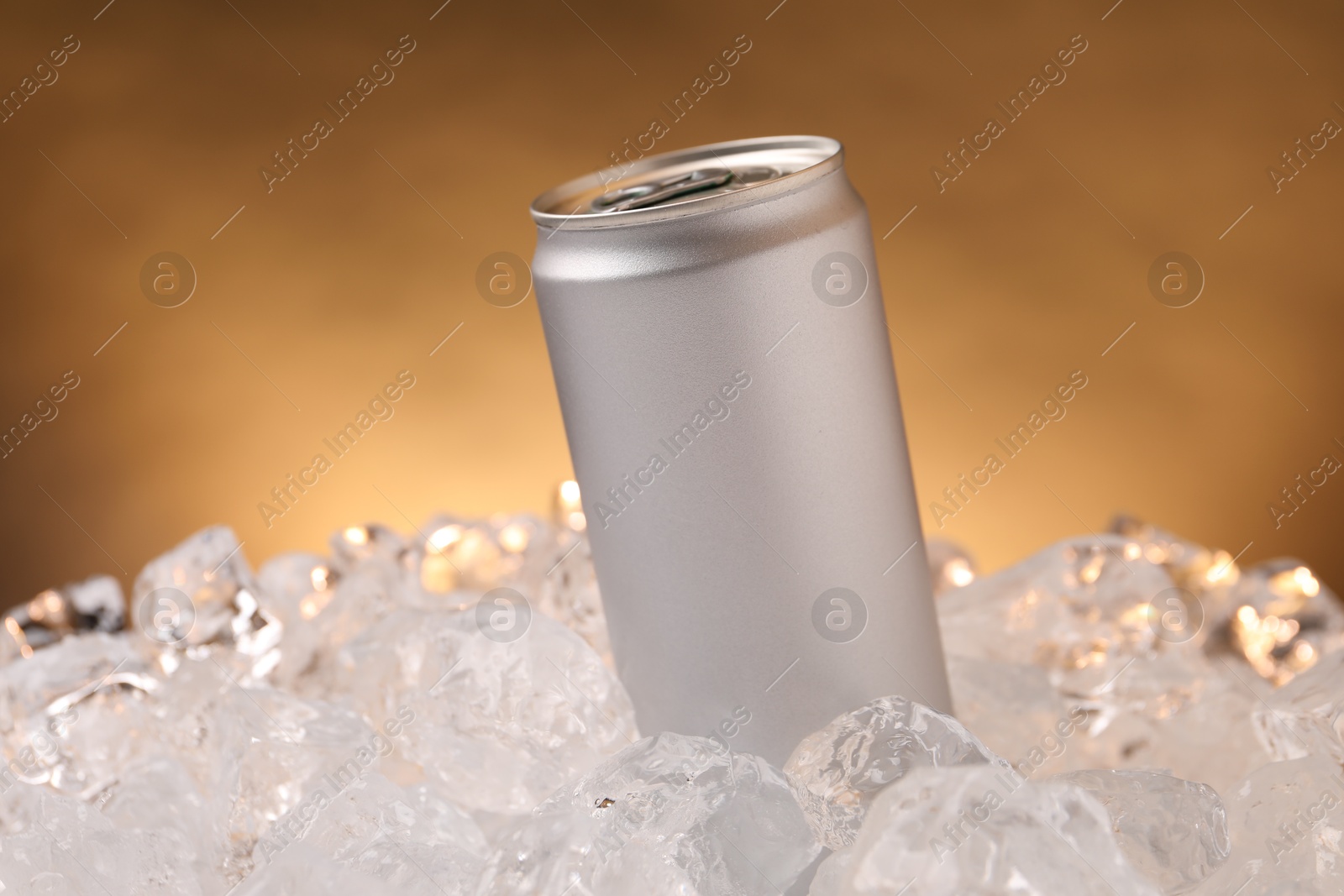 Refreshing drink in can on ice cubes against golden background, closeup Photo of Refreshing drink in can on ice cubes against golden background, closeup