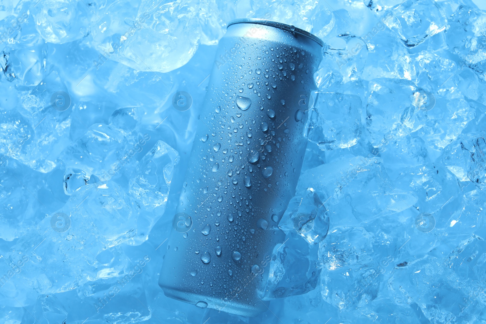 Refreshing drink in can on ice cubes, top view. Toned in blue Photo of Refreshing drink in can on ice cubes, top view. Toned in blue