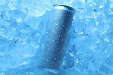 Photo of Refreshing drink in can on ice cubes, top view. Toned in blue