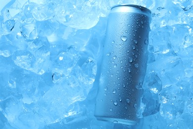 Photo of Refreshing drink in can on ice cubes, top view. Toned in blue