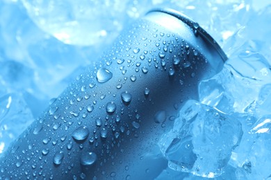 Photo of Refreshing drink in can on ice cubes, closeup. Toned in blue