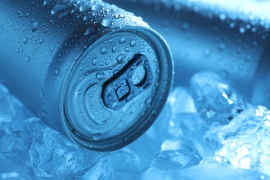 Photo of Refreshing drinks in cans on ice cubes, closeup. Toned in blue