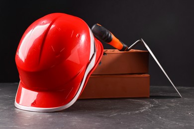 Bricks, hardhat and bucket trowel on grey table