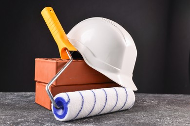 Bricks, hardhat and paint roller on grey table