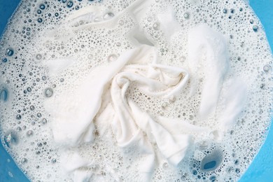 Photo of White clothes soaked in water before washing, top view