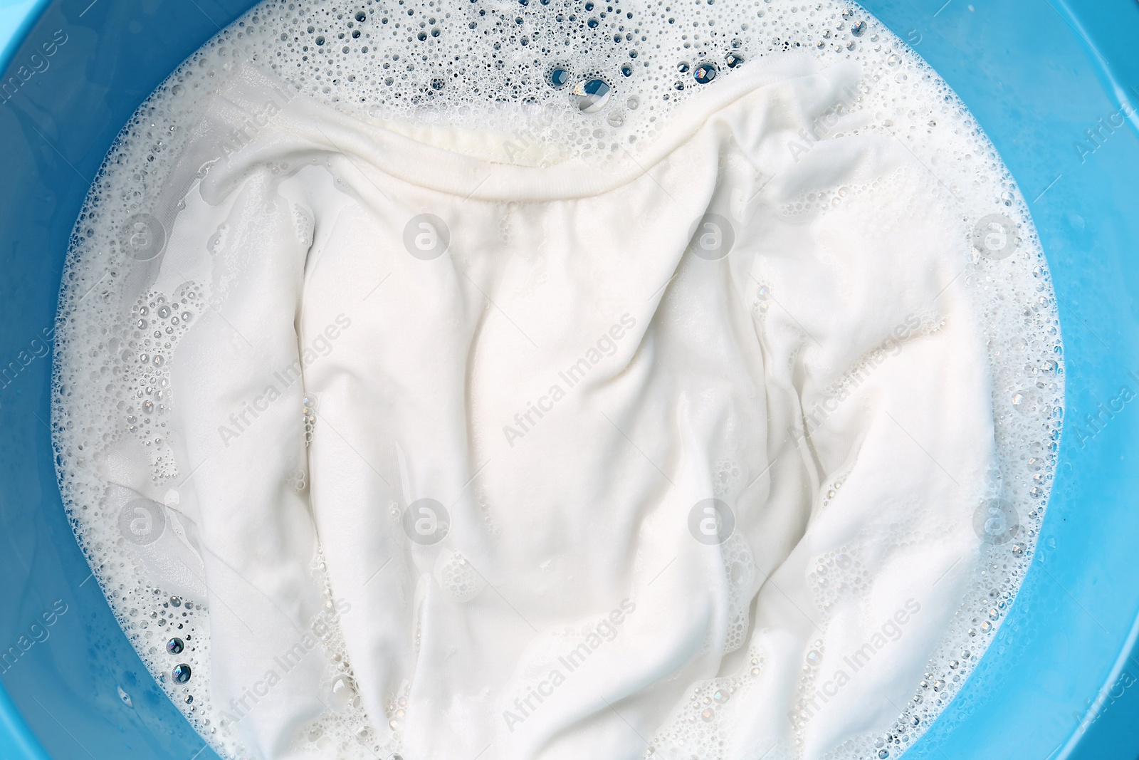 Photo of White clothes soaked in water before washing, top view