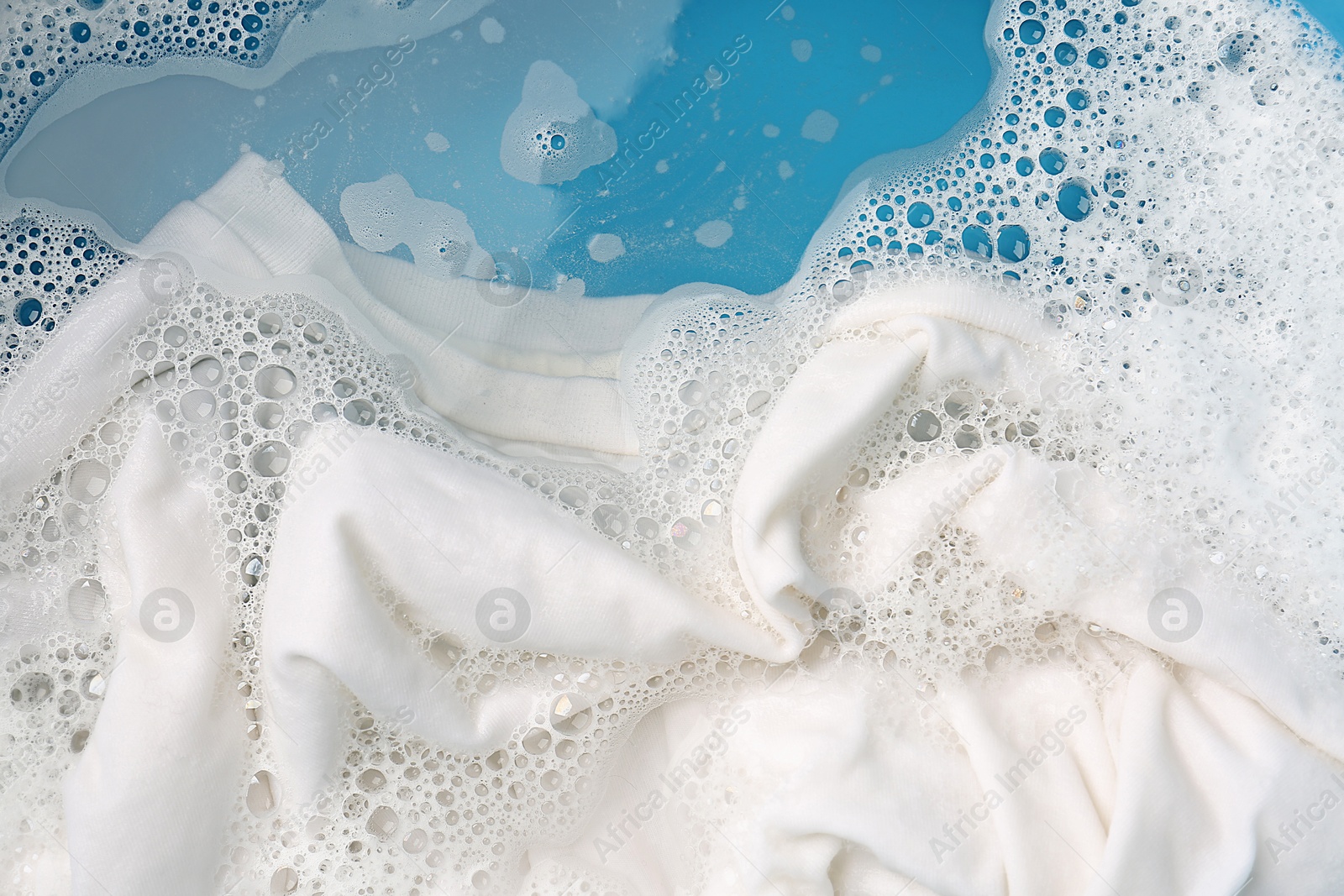 Photo of White clothes soaked in water before washing, top view