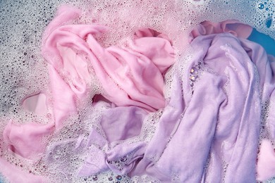 Photo of Colorful clothes soaked in water before washing, top view