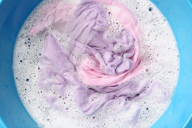 Photo of Colorful clothes soaked in water before washing, top view