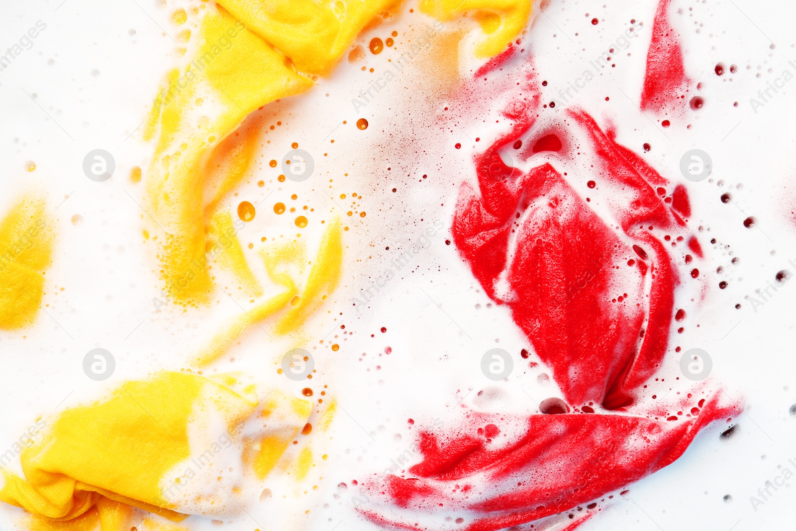 Photo of Colorful clothes soaked in water before washing, top view