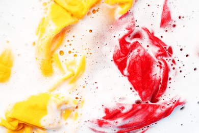 Photo of Colorful clothes soaked in water before washing, top view