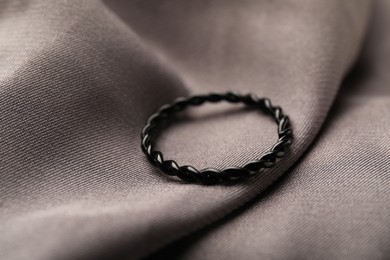 One stylish ring on grey cloth, closeup