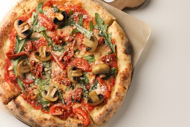 Photo of Tasty pizza with mushrooms, tomatoes and arugula on white table, top view