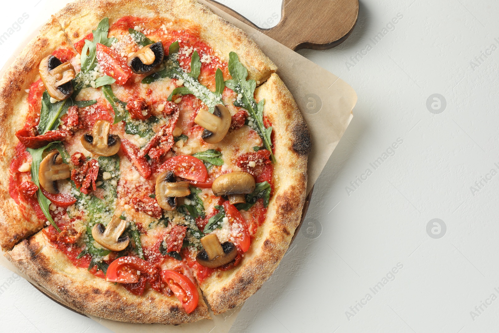 Photo of Tasty pizza with mushrooms, tomatoes and arugula on white table, top view. Space for text