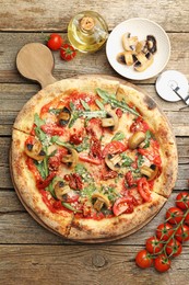 Photo of Tasty pizza with mushrooms, tomatoes, arugula and cutter on wooden table, flat lay