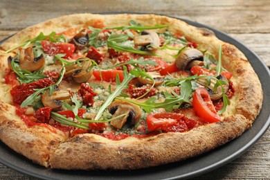 Photo of Tasty pizza with mushrooms, tomatoes and arugula on wooden table, closeup