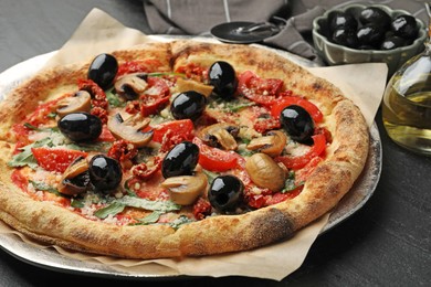 Photo of Tasty pizza with mushrooms, olives and arugula on black table, closeup