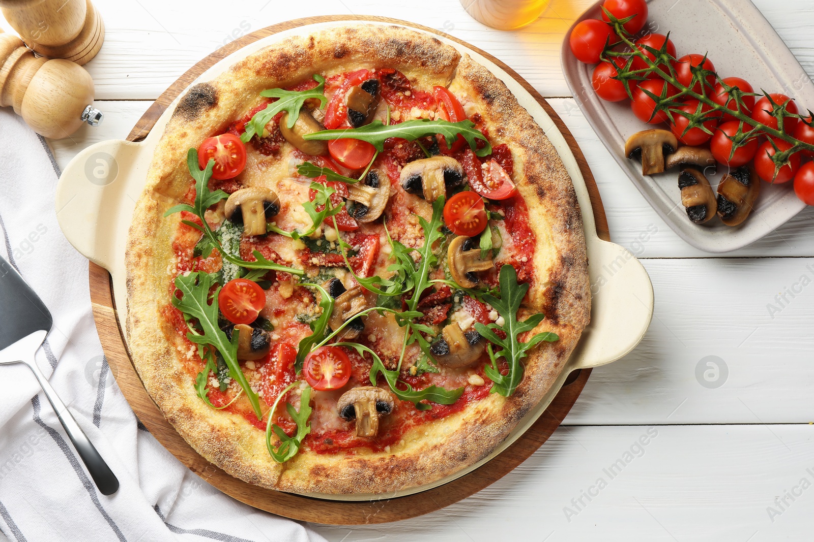 Tasty pizza with mushrooms, tomatoes, arugula and server on white wooden table, flat lay Photo of Tasty pizza with mushrooms, tomatoes, arugula and server on white wooden table, flat lay