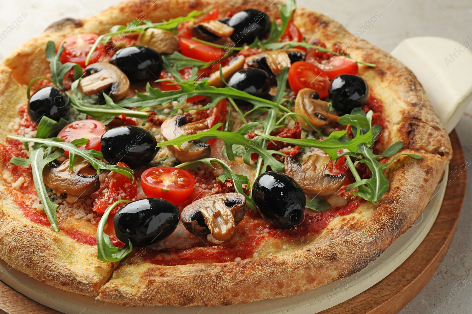 Tasty pizza with mushrooms, black olives and arugula on light grey table, closeup Photo of Tasty pizza with mushrooms, black olives and arugula on light grey table, closeup