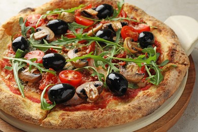 Photo of Tasty pizza with mushrooms, black olives and arugula on light grey table, closeup