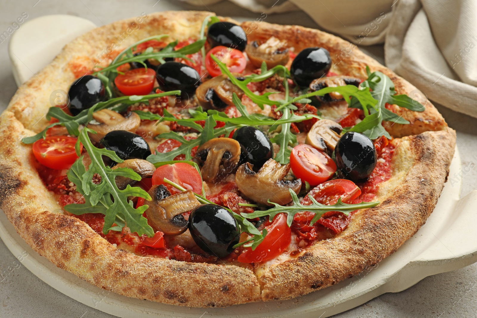 Photo of Tasty pizza with mushrooms, black olives and arugula on light grey table, closeup