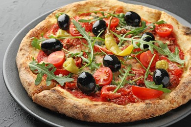 Photo of Tasty pizza with tomatoes, olives, chili and arugula on black table, closeup