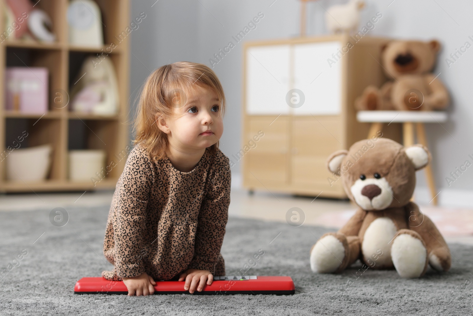 Photo of Cute little girl playing with toy piano at home