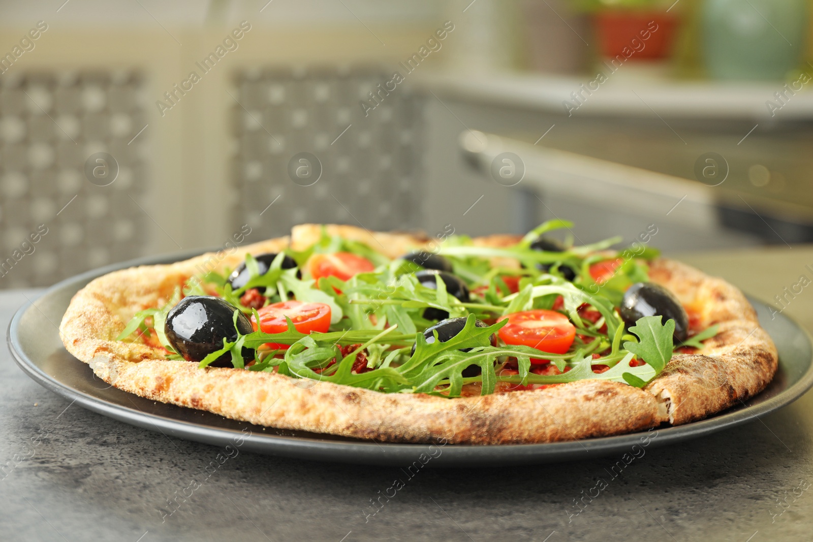 Photo of Delicious pizza with olives, cherry tomatoes and arugula on grey table indoors, closeup