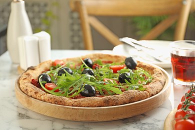 Delicious pizza with olives, cherry tomatoes, arugula and soda drink on white marble table indoors, closeup