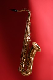 Photo of Jazz. One golden saxophone on red background