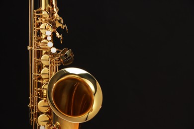 Photo of Jazz. One beautiful saxophone on black background, closeup. Space for text