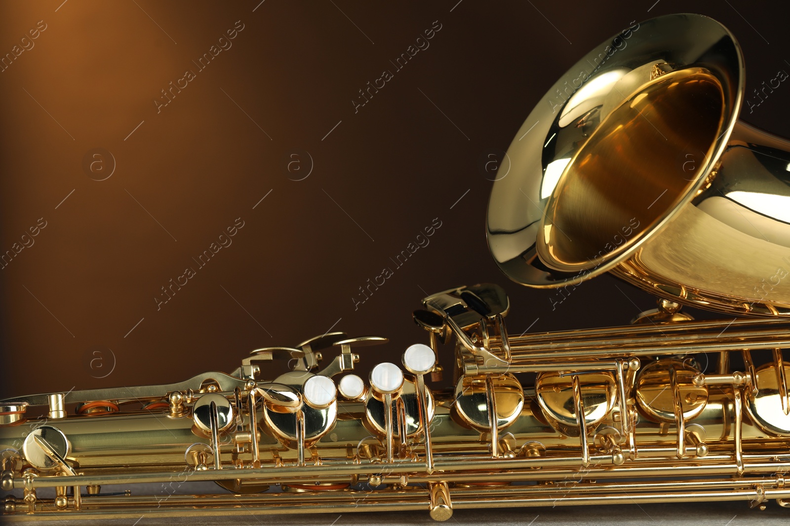 Photo of Jazz. One beautiful saxophone on brown background, closeup. Space for text