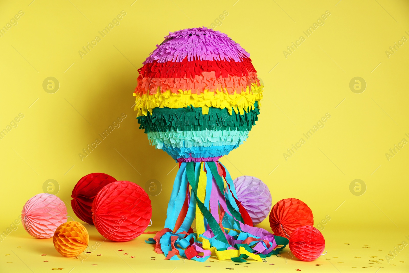 Photo of Colorful pinata and party decor on yellow background