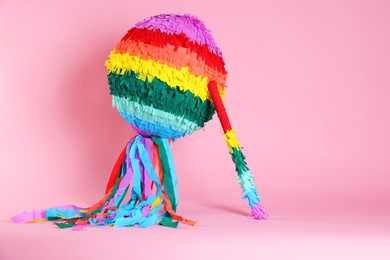 Photo of Colorful pinata and stick on pink background, space for text