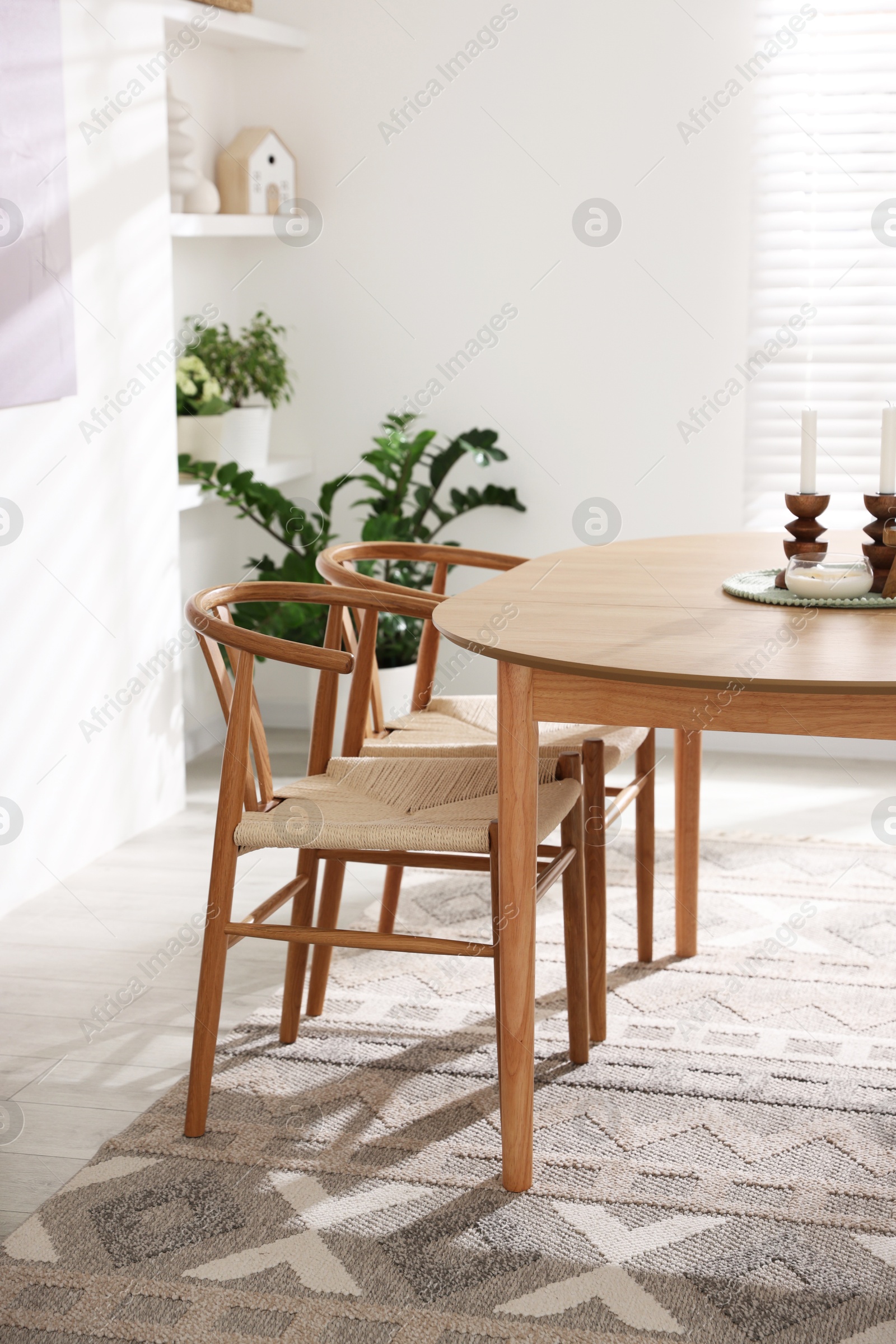 Photo of Wooden table with candles, chairs and houseplants in room