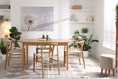 Photo of Stylish room with wooden table, chairs and houseplants. Interior design