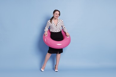 Photo of Businesswoman with inflatable ring on light blue background