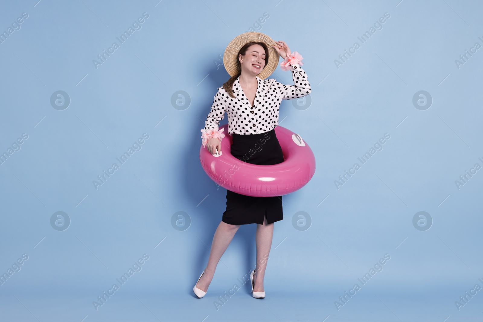 Photo of Businesswoman with inflatable ring, straw hat and flower bracelets on light blue background