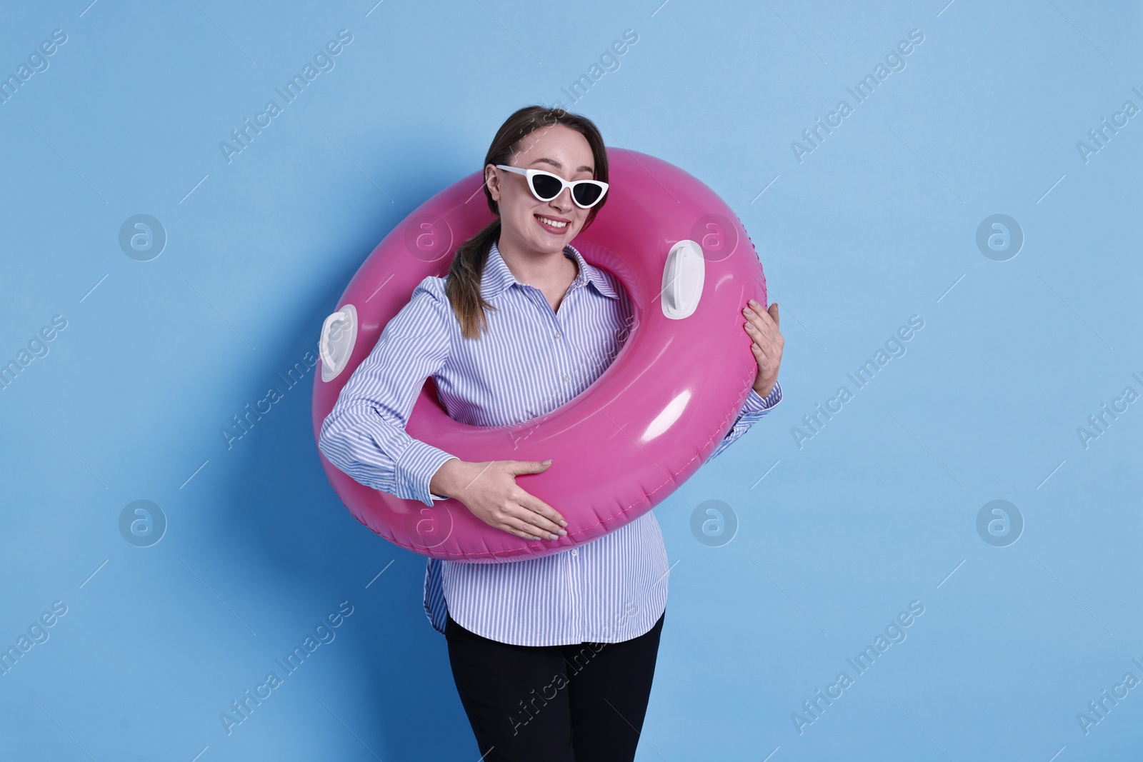 Photo of Businesswoman with inflatable ring and sunglasses on light blue background