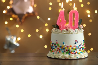 Photo of 40th birthday. Tasty cake with burning number shaped candles and sprinkles on wooden table against blurred background with lights, space for text. Bokeh effect