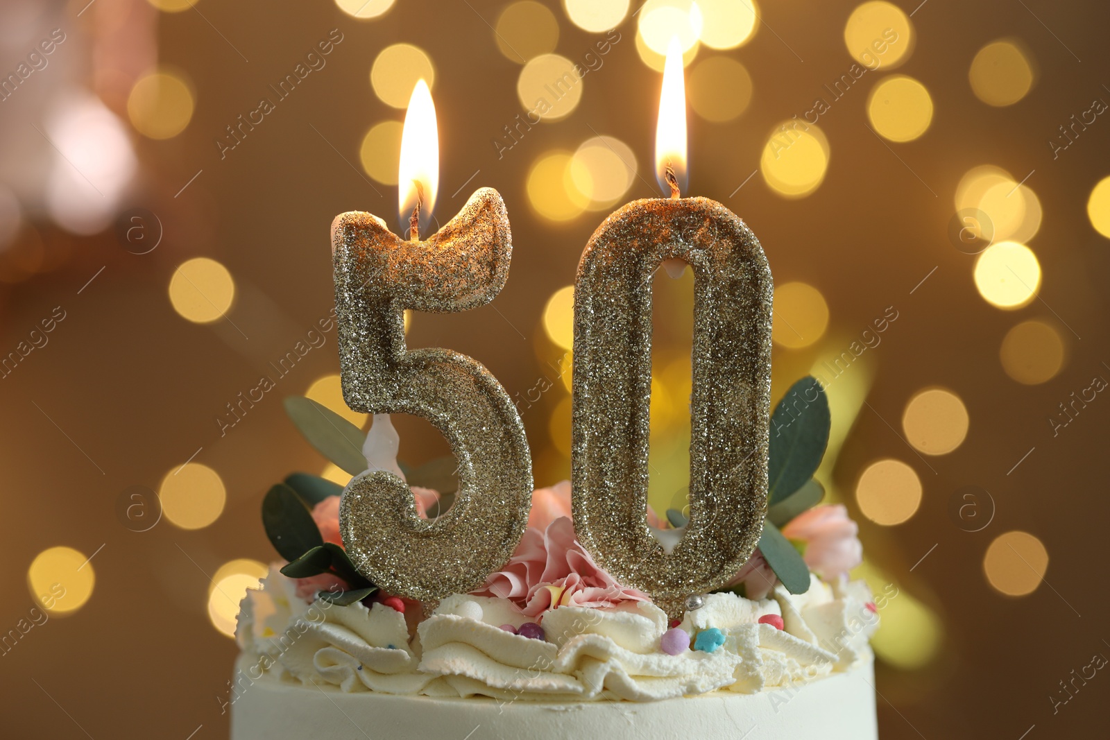 Photo of 50th birthday. Tasty cake with burning number shaped candles and sprinkles on blurred background with lights, closeup. Bokeh effect