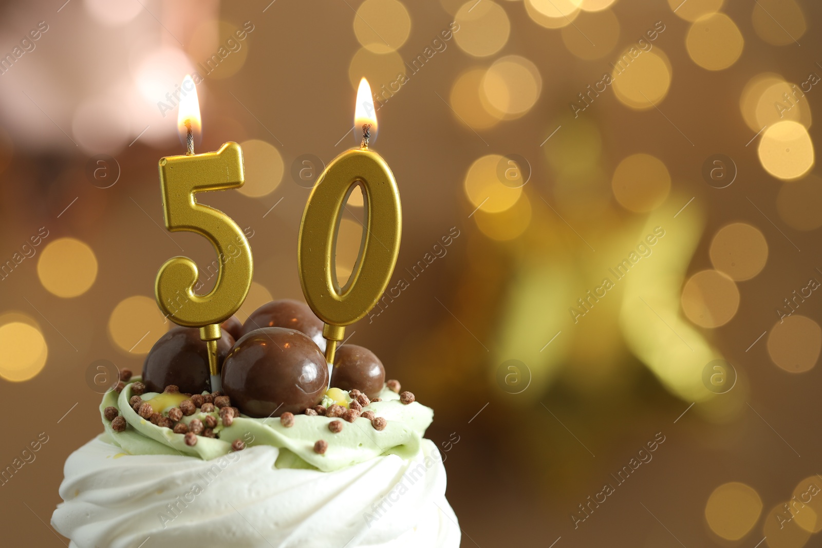 Photo of 50th birthday. Tasty cupcake with burning number shaped candles on blurred background with lights, space for text. Bokeh effect