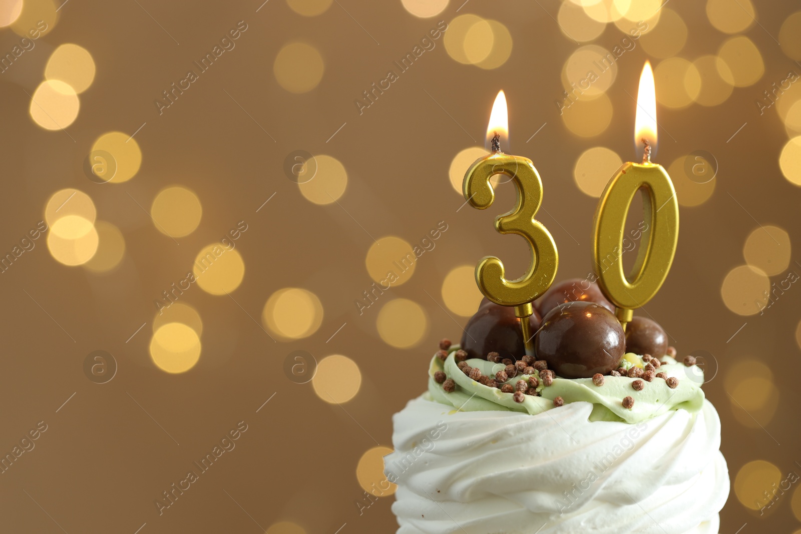 Photo of 30th birthday. Tasty cupcake with burning number shaped candles on blurred background with lights, space for text. Bokeh effect