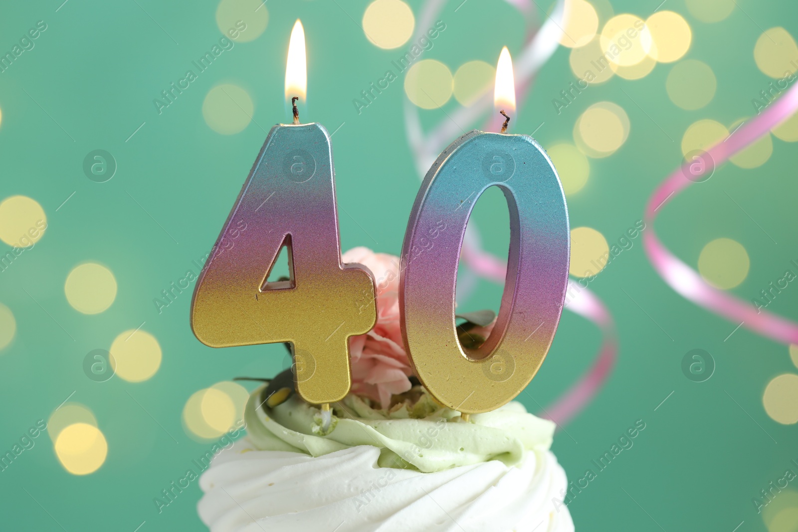 Photo of 40th birthday. Tasty cupcake with burning number shaped candles on turquoise background with blurred lights, closeup. Bokeh effect