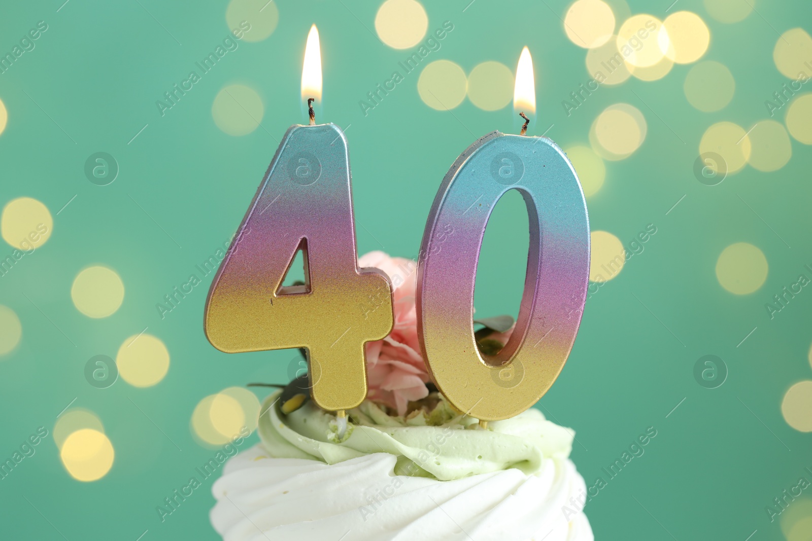 Photo of 40th birthday. Tasty cupcake with burning number shaped candles on turquoise background with blurred lights, closeup. Bokeh effect