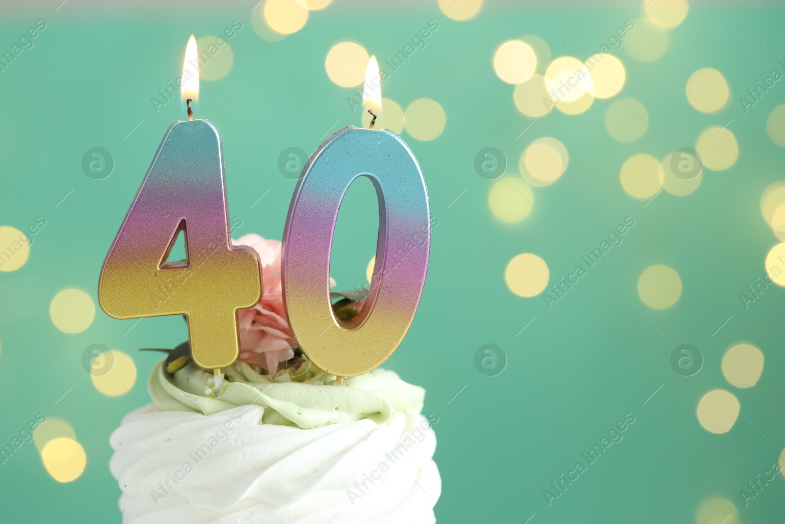 Photo of 40th birthday. Tasty cupcake with burning number shaped candles on turquoise background with blurred lights, closeup. Bokeh effect