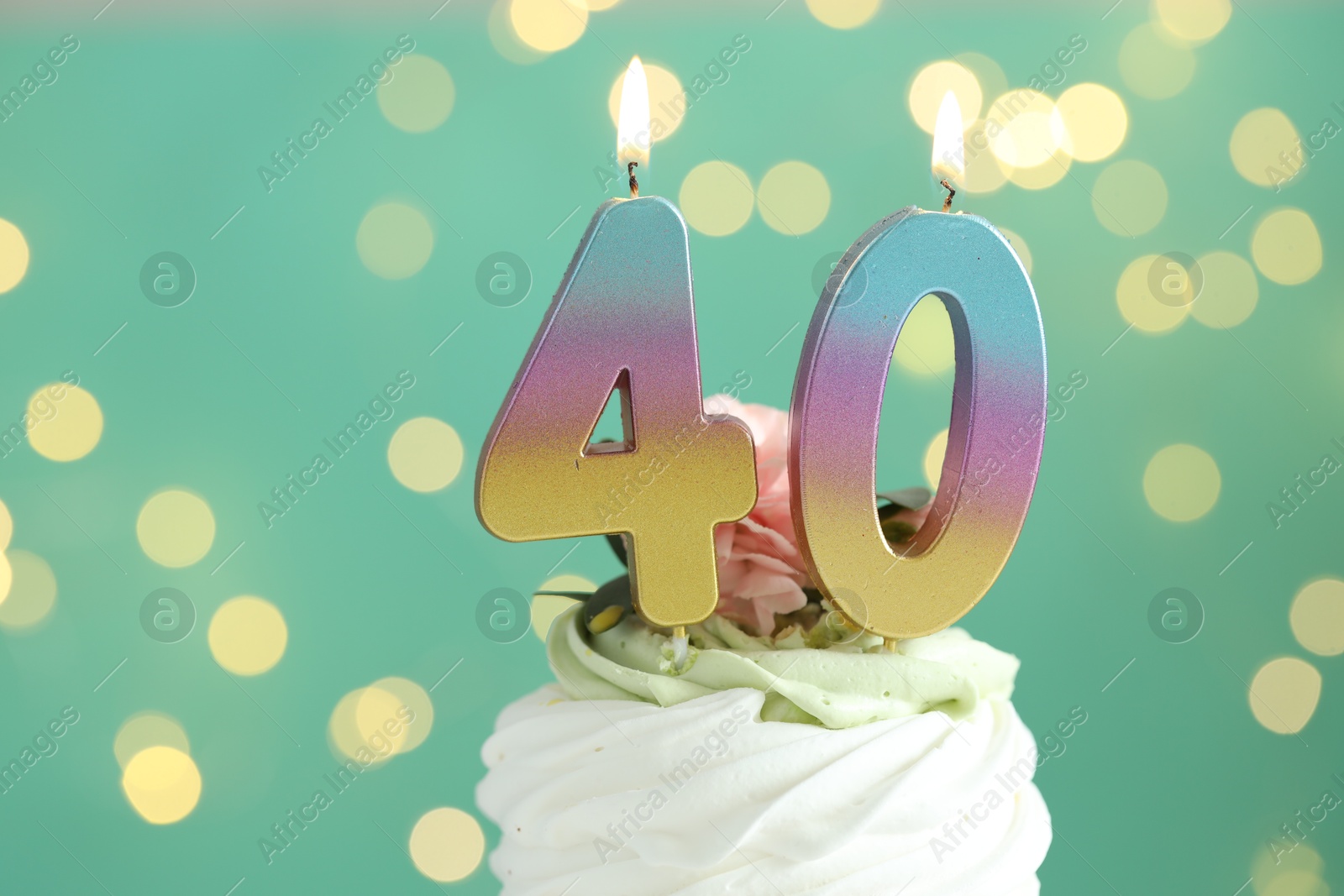 Photo of 40th birthday. Tasty cupcake with burning number shaped candles on turquoise background with blurred lights, closeup. Bokeh effect