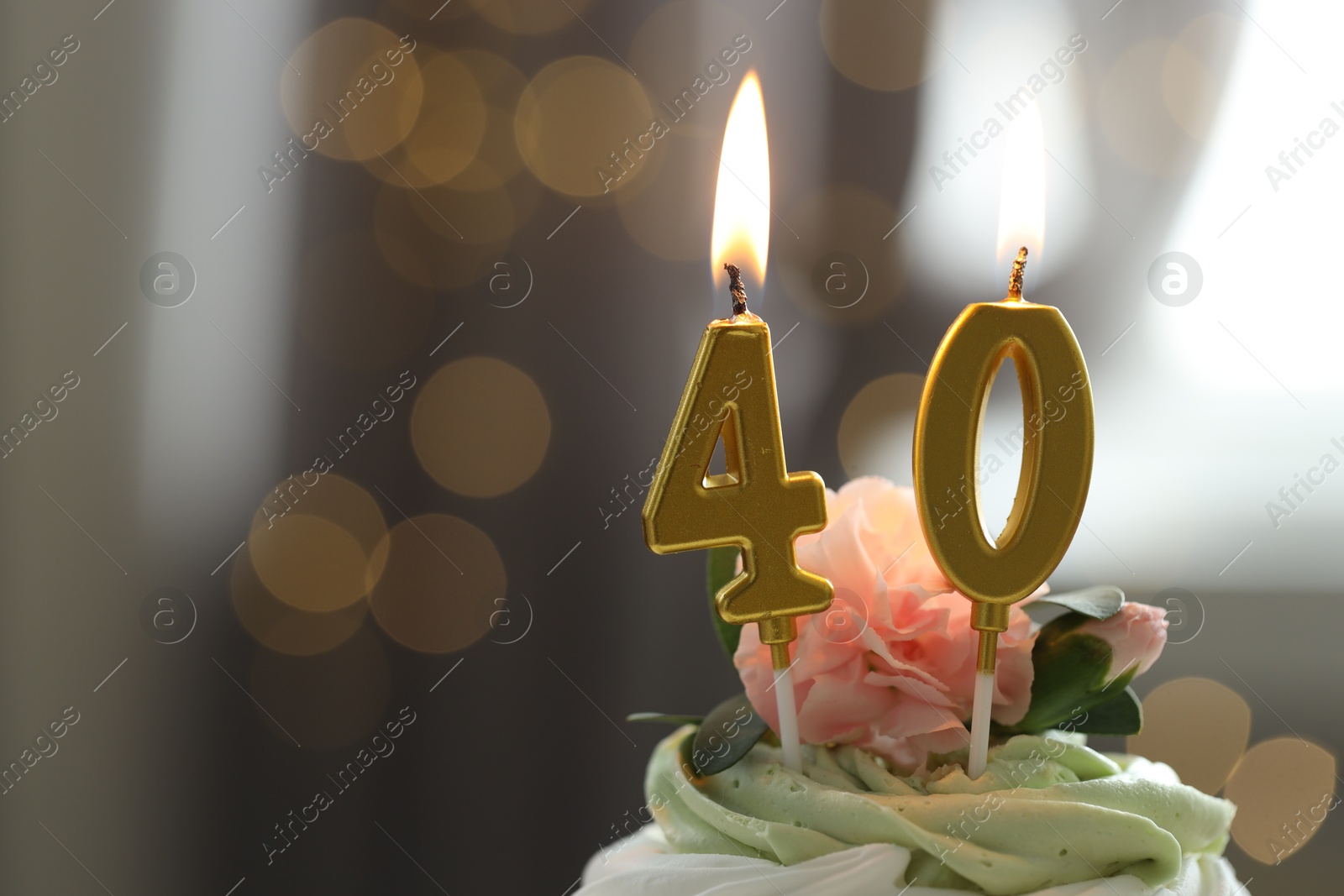 Photo of 40th birthday. Tasty cupcake with burning number shaped candles on blurred background with lights, space for text. Bokeh effect